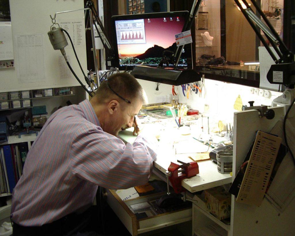 watchmaker repairing watches underneath a light